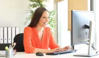 Businesswoman wearing an orange blouse working typing in a desktop computer at office